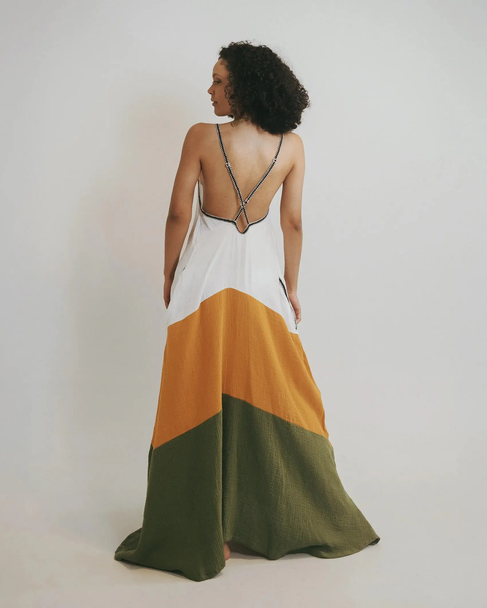 Vestido largo con escote V profundo en delantero y espalda con ajuste cruzado ajustable en hiladillo, cortes horizontales con fleco y bolsillos.