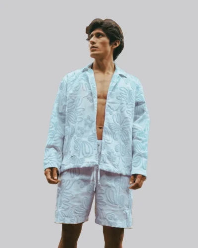 Set de camisa tipo chaqueta sin abotonadura, cuello sport, solapa pespuntada, tubo de ajuste por cordón visible, manga larga recta sin puño, y short clásico.